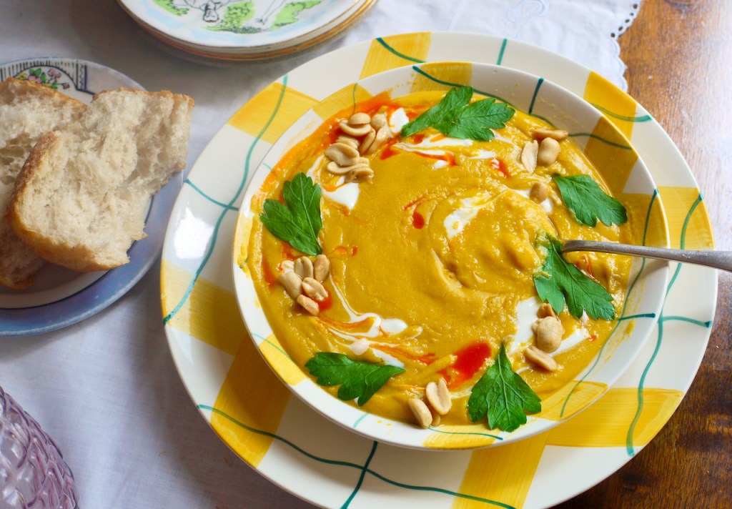 A bowl of soup with a spoon in it and bread on the side.